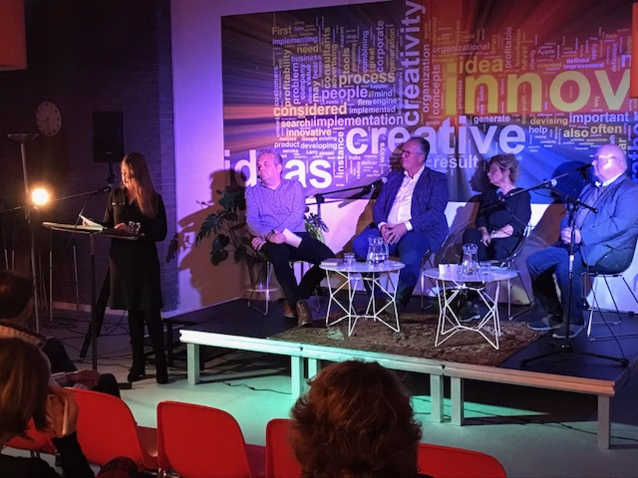 Paneldiscussie over laaggeletterdheid met spreker Arjan Kampman en publiek, woordwolk creatieve innovatie ideeën, thema auto rijdt op benzine