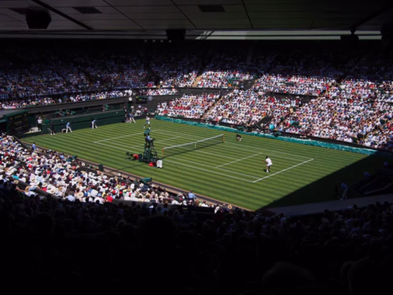 Sportoverzicht 27 juni - 3 juli 2022 met wimbledon tenniswedstrijd in vol stadion op grasbaan, spelers aan het serveren, scheidsrechter zichtbaar