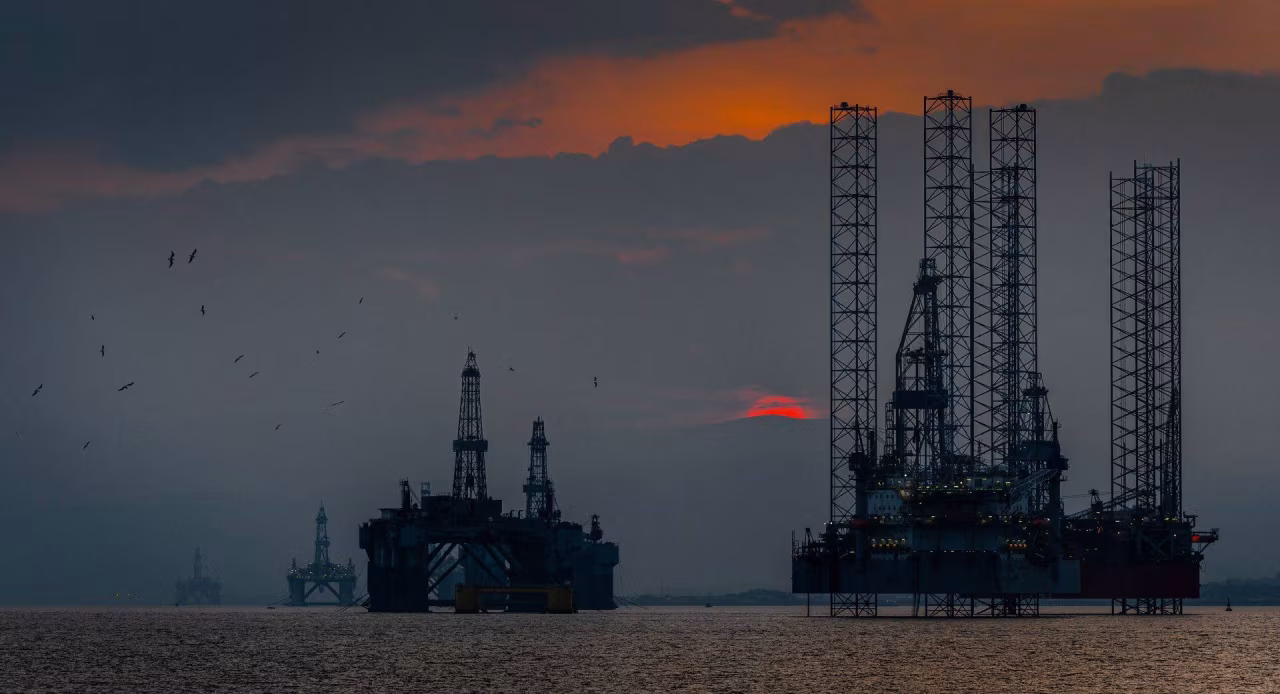 Nieuwsoverzicht 13-19 juni 2022 met foto van drie offshore boorplatformen in Noordzee bij zonsondergang, benadrukt gaswinning en energie-industrie