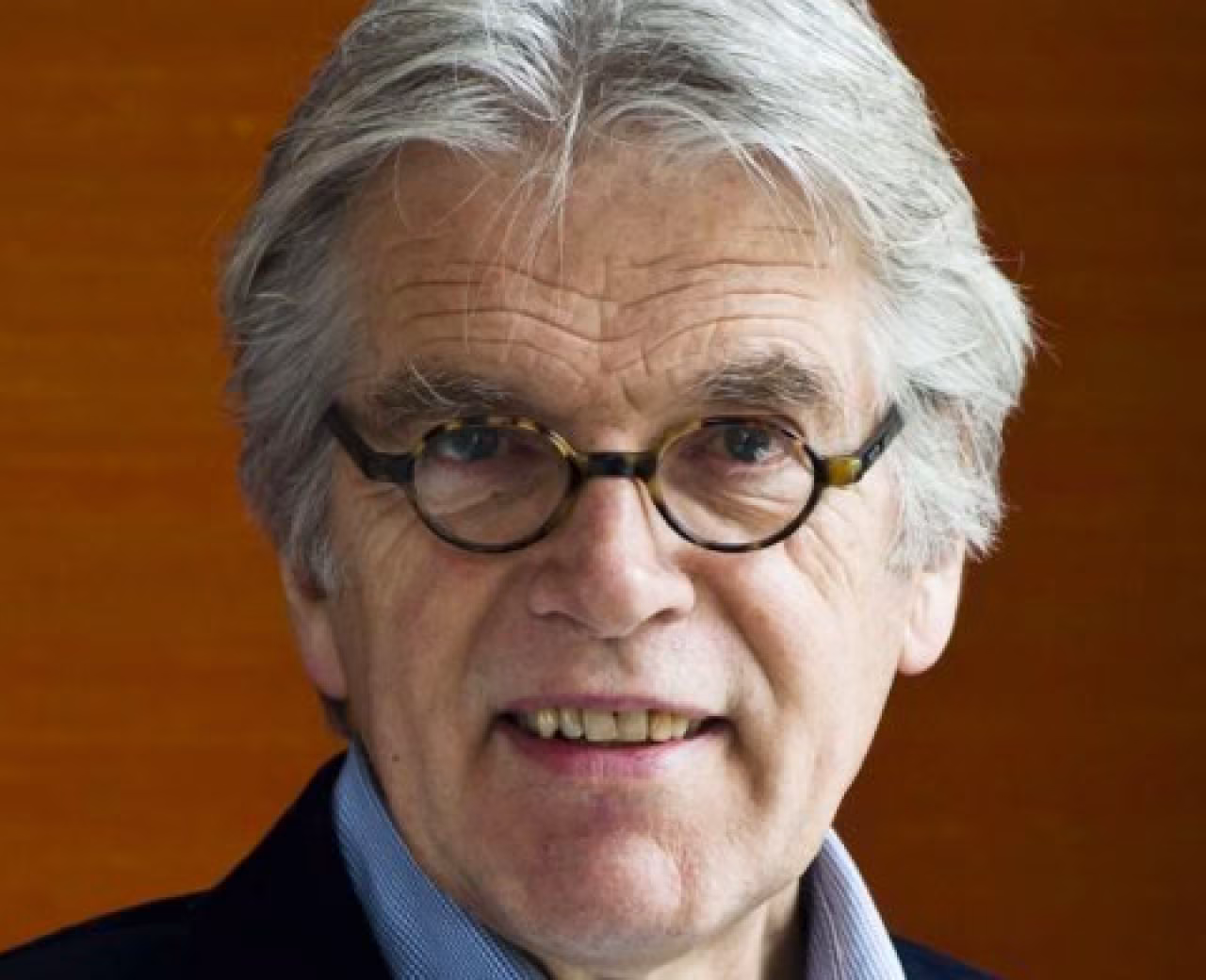 Portret van een grijze man met bril, artikel over Twente Stad en de toekomst van Twente met columnist Theo Hakkert