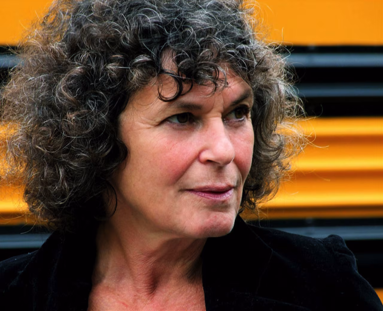 Close-up portret hoofd met krullend haar kijkt naar rechts oranje zwarte strepen achtergrond h2 titel: twee bijeenkomsten over laaggeletterdheid