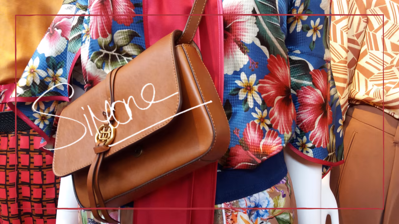 Close-up etalagepop met kleurrijk bloemmotief, lichtbruine leren tas met goudlogo, tekst sienne, langer plezier van je nieuwe tas
