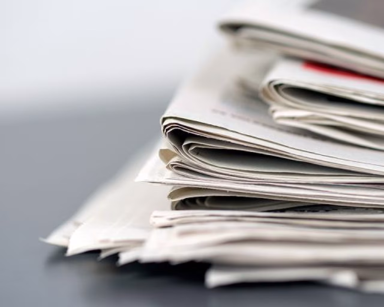 Stapel opgevouwen kranten op tafel met focus op pagina's en vouwen, thema nieuws en informatie, het weekoverzicht van maandag 22 t/m zondag 28 november