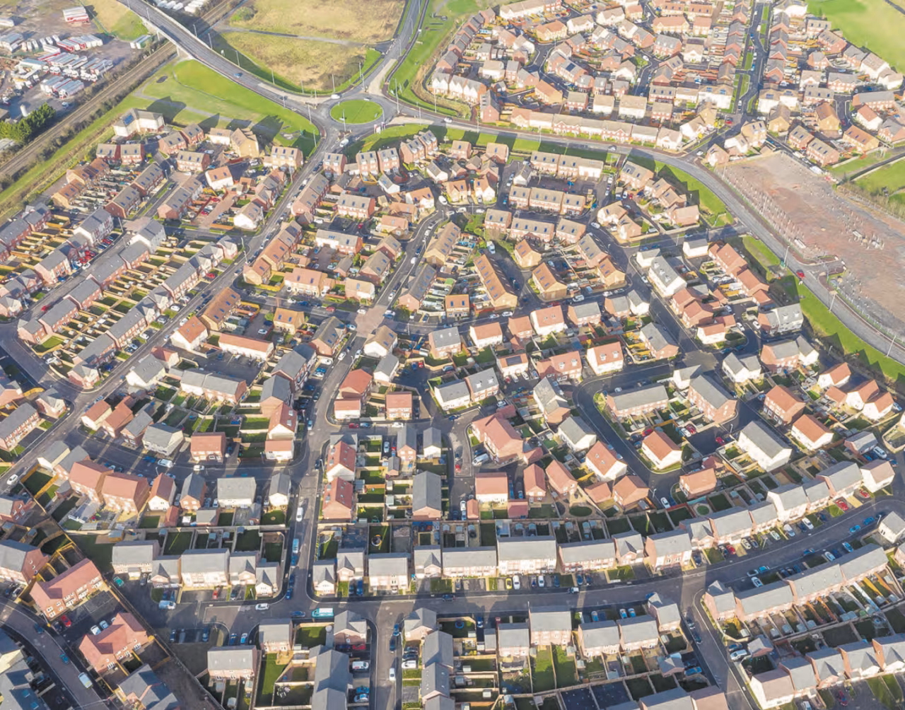 Luchtfoto van een spiraalvormige woonwijk met dichtbebouwde huizen en rotonde bovenaan, leef twente en tkkr win win-situatie