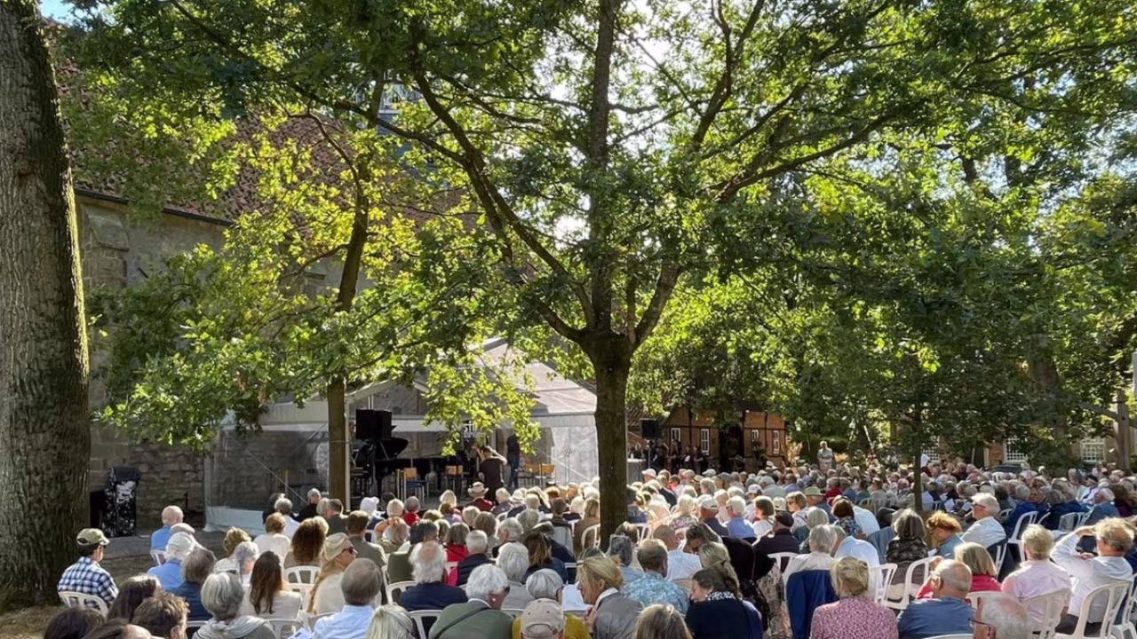 Spetterend slotakkoord van stralend stiftfestival groot buitenconcert met veel mensen op grasveld bij stiftskerk