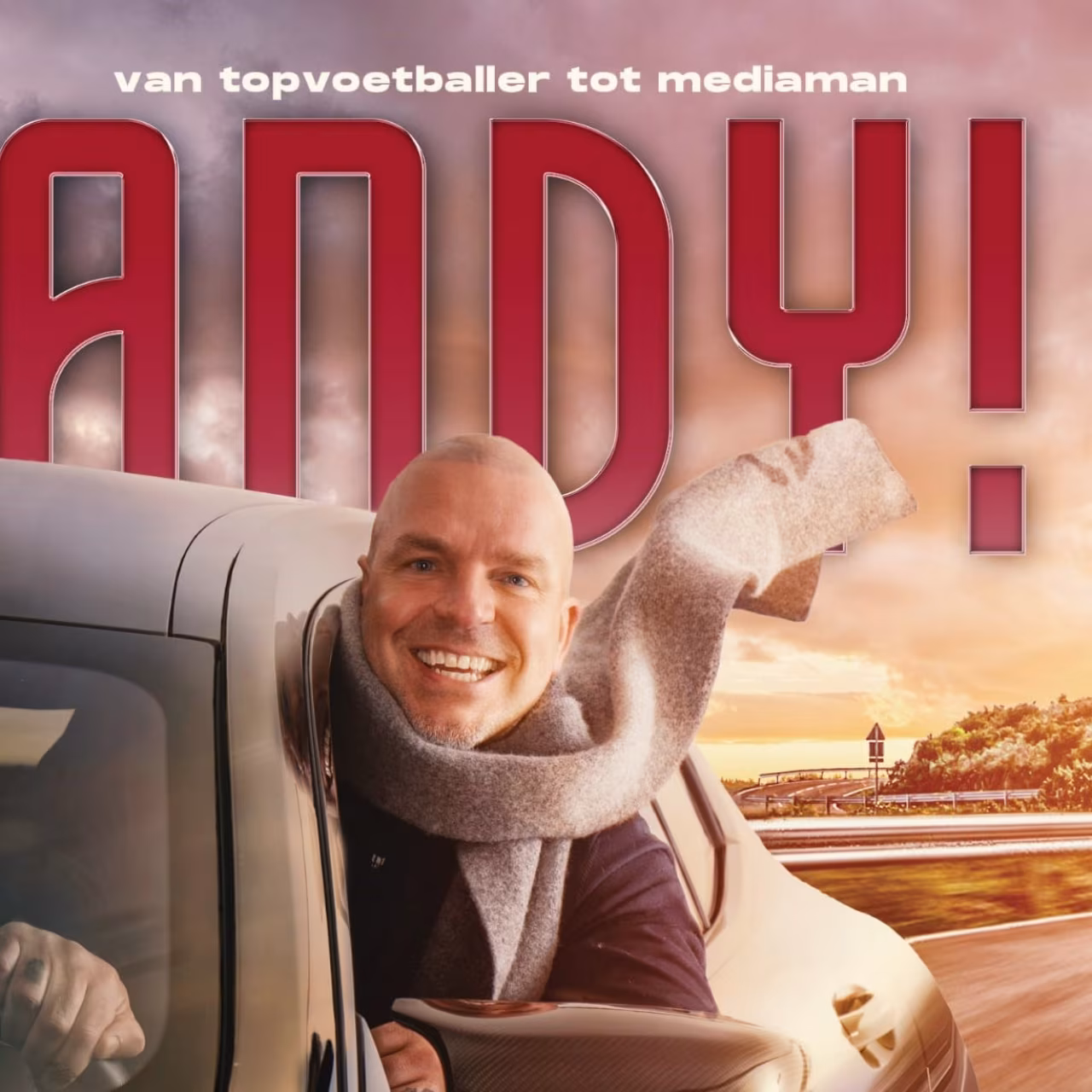 Andy! boekcover van topvoetballer tot mediaman met lachend gezicht uit autovenster, sjaal wappert, zonsondergang achtergrond