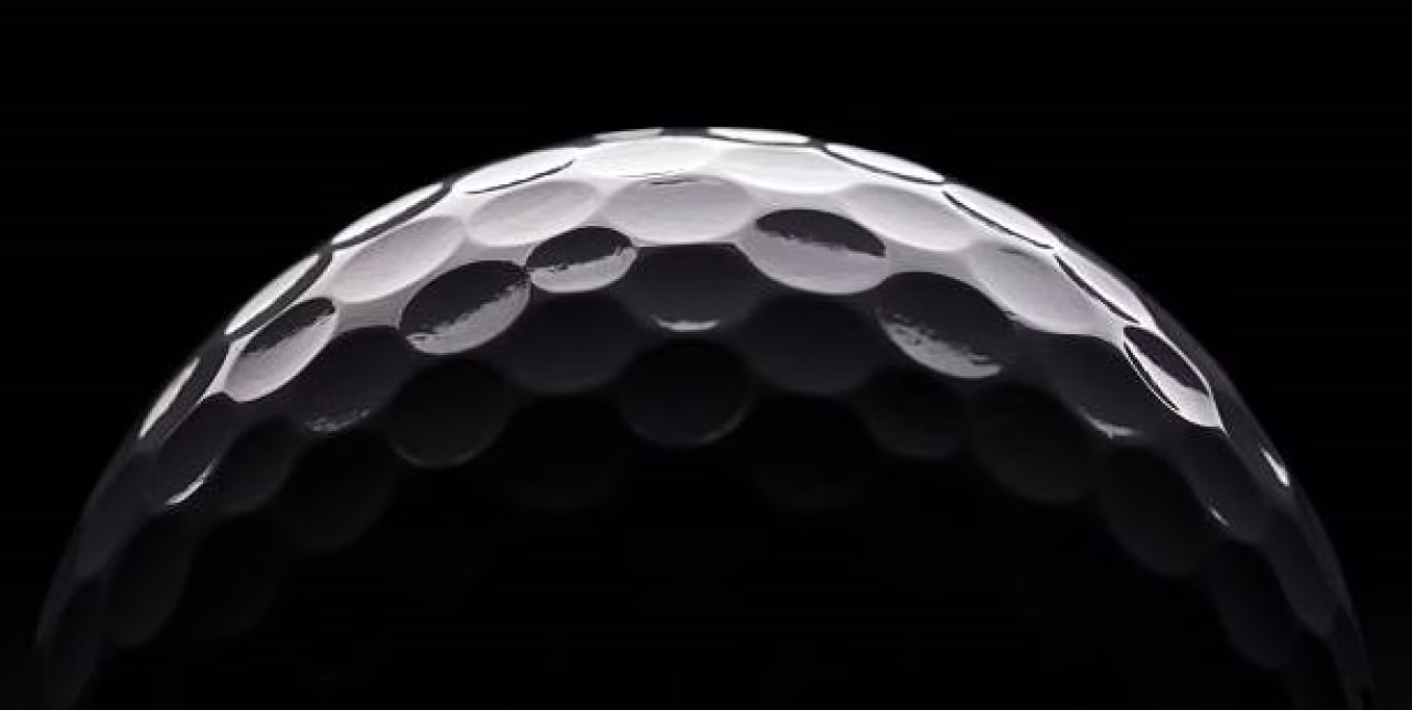 Close-up golfbal met duidelijke putjes tegen zwarte achtergrond bij artikelen over golf etiquette en Twentse natuur