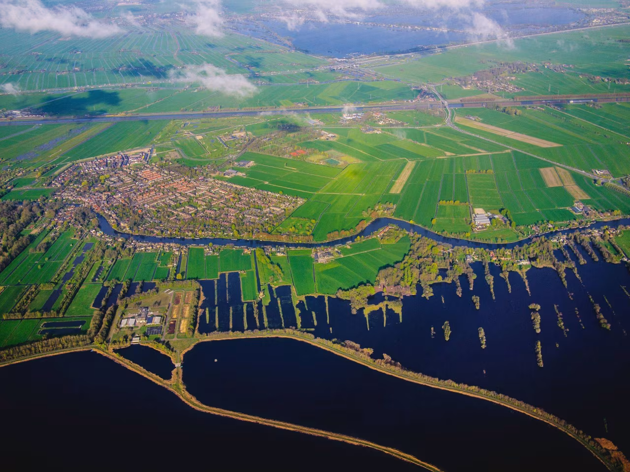 Luchtfoto toont Nederlands landschap met woongebied links, landbouwvelden en waterpartijen rechts nieuwsoverzicht 1 7 mei 2023
