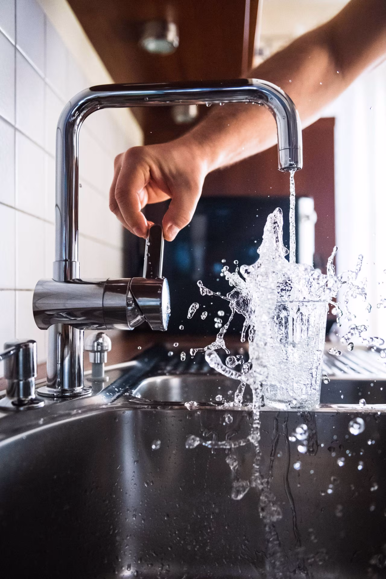 Keukenaanrecht met moderne chromen kraan en stromend water in glas, thema Droge Januari uit twents mediaplatform