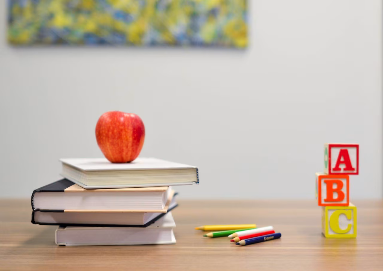 Nieuwsoverzicht 21 t/m 27 augustus 2023 met foto van boekenstapel, appel en kleurpotloden symboliseert leren en onderwijs