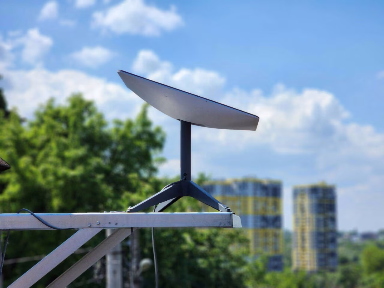 Satellietschotel op metalen steun buiten met bomen en hoge gebouwen op achtergrond nieuwsoverzicht van ma 10 maart t/m zo 16 maart 2025