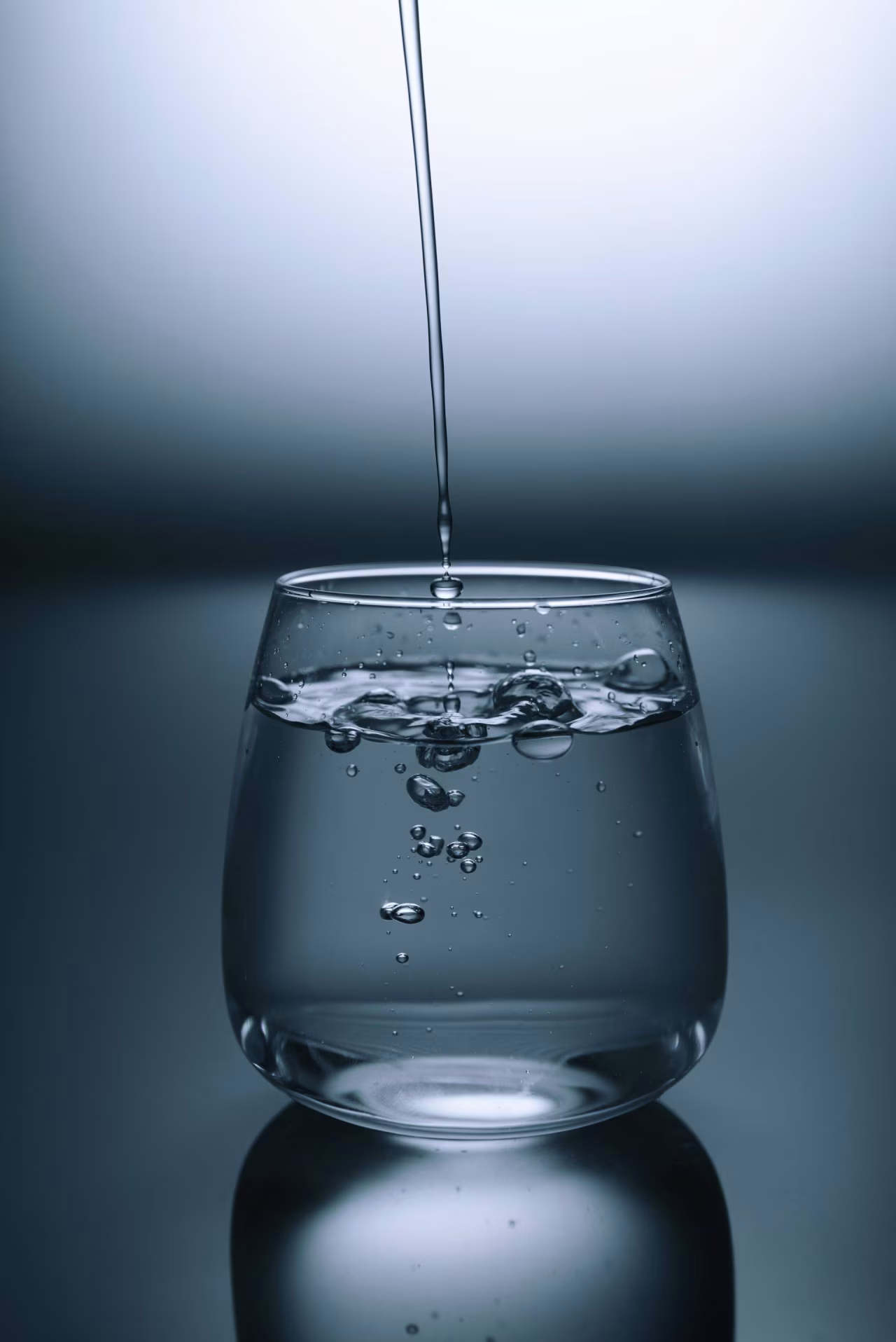 Glas driekwart gevuld met water met bubbels en vallend water voor bericht uit het rampgebied over drinkwaterverontreiniging