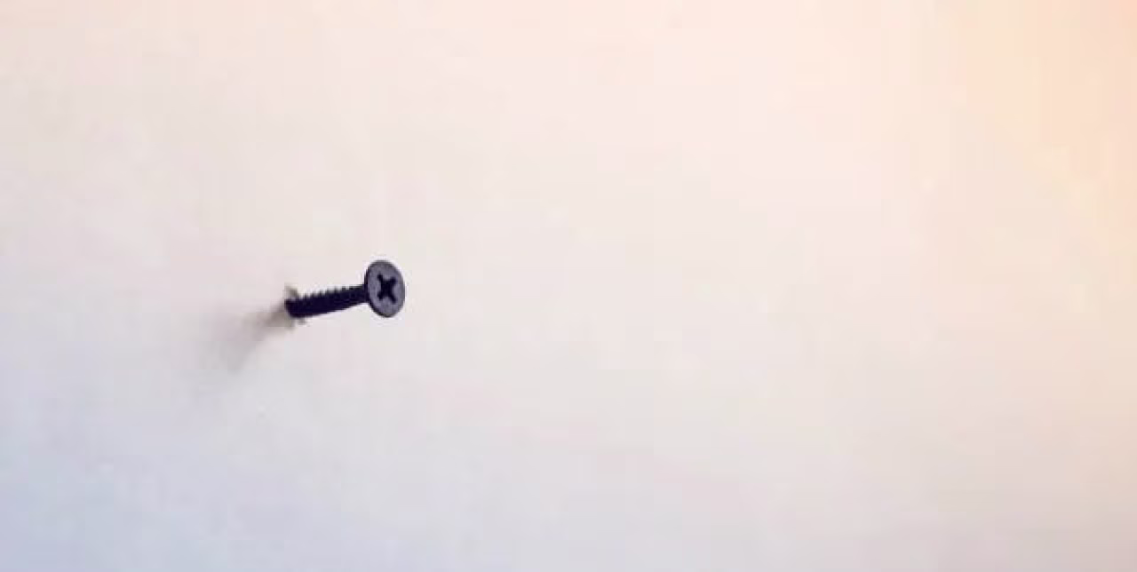 Kunststuk tkkrs website toont een schroef halverwege uit muur met kruisvormige kop