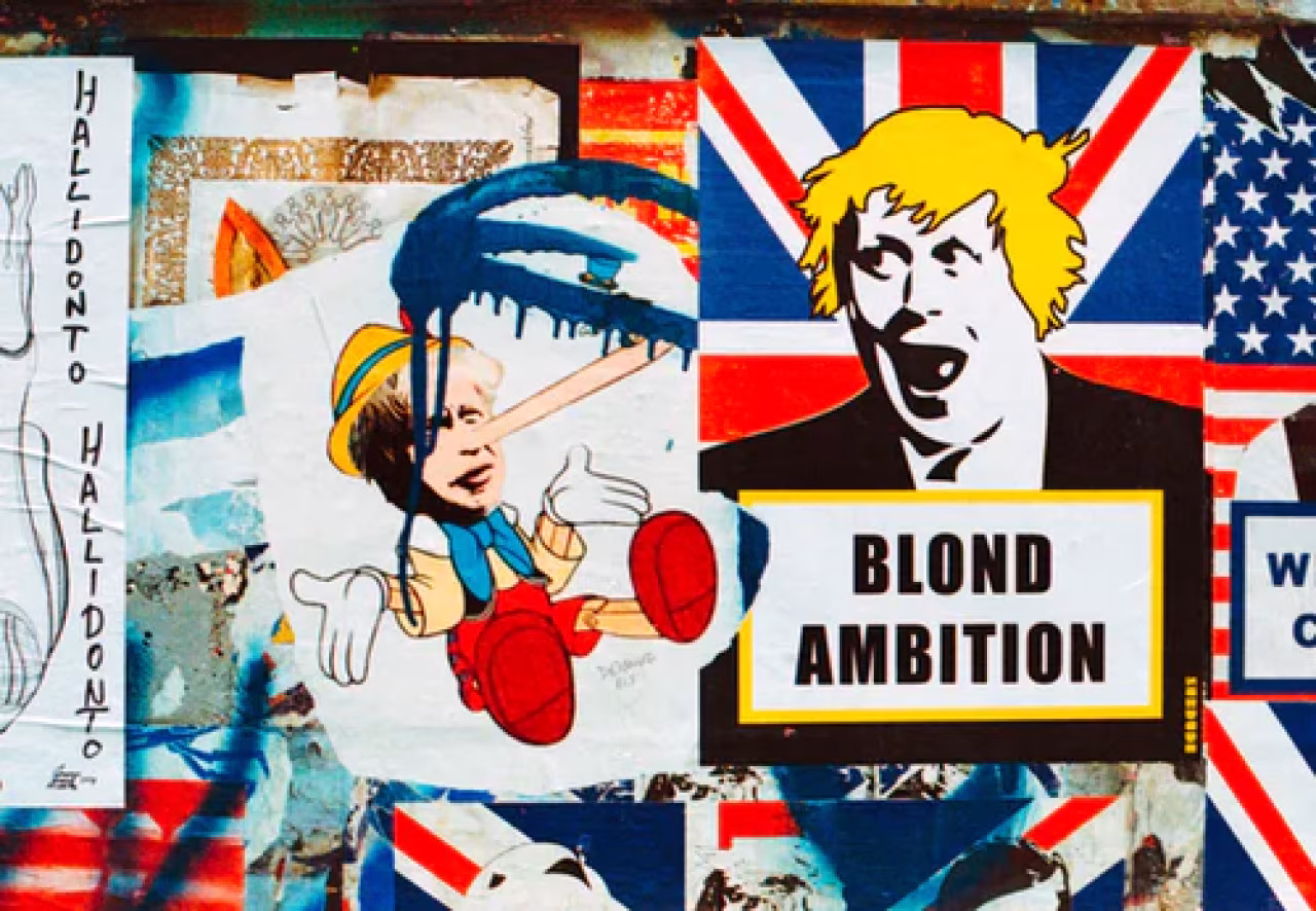 Collage straatkunst met Brits vlagmotief en tekst Blond Ambition, Pinokkio met lange neus als satire op Boris Johnson naast nieuwsweek