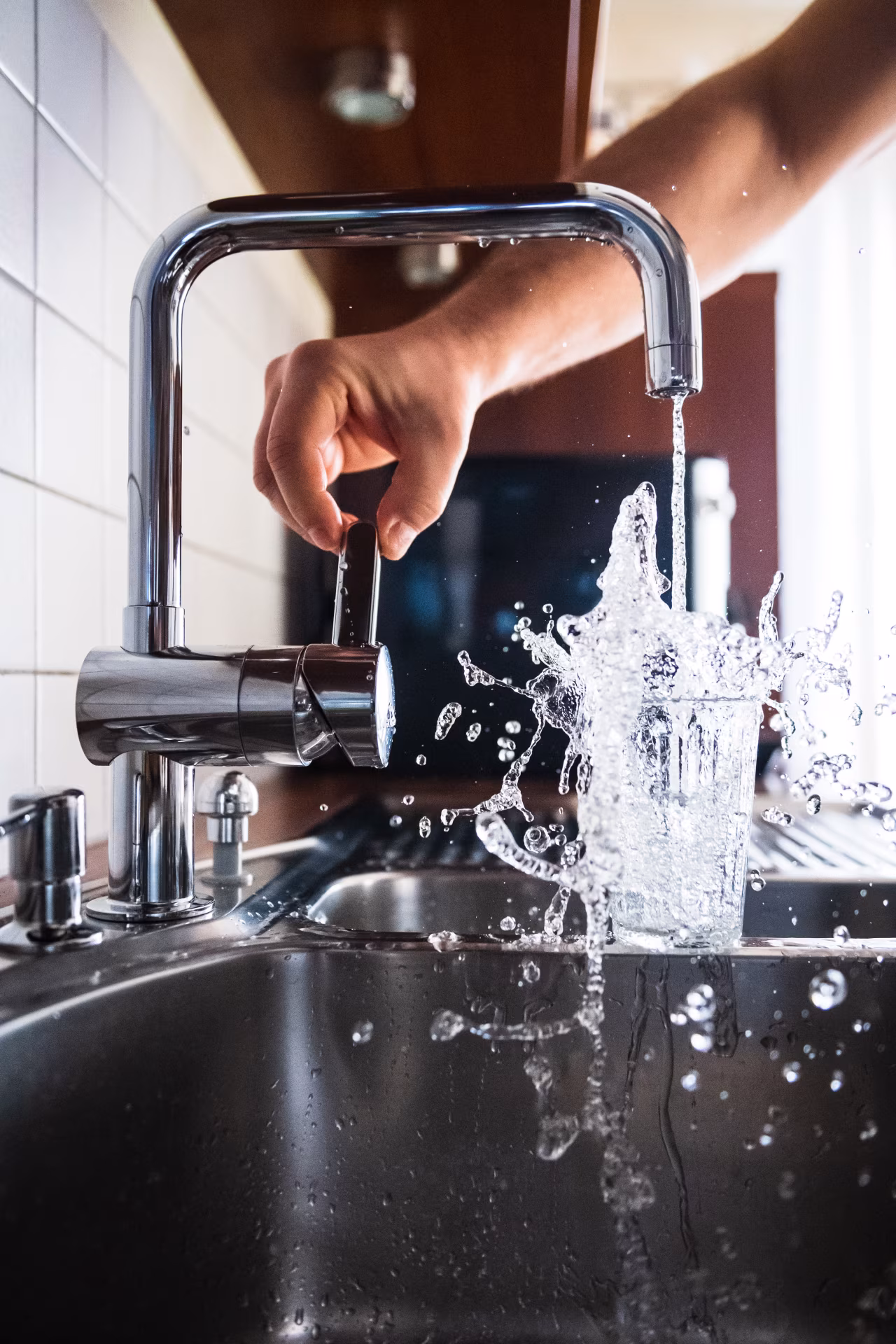 Keukenaanrecht met moderne chromen kraan en stromend water in glas, thema Droge Januari uit twents mediaplatform