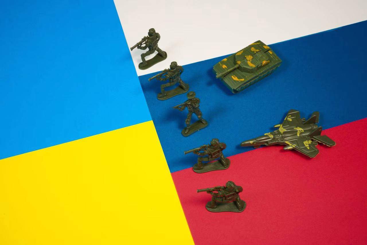 Vierkleurig vlak met Oekraïne en Rusland vlaggen en groene speelgoed militairen en voertuigen symboliseren oorlog in Oekraïne 20-26 mei