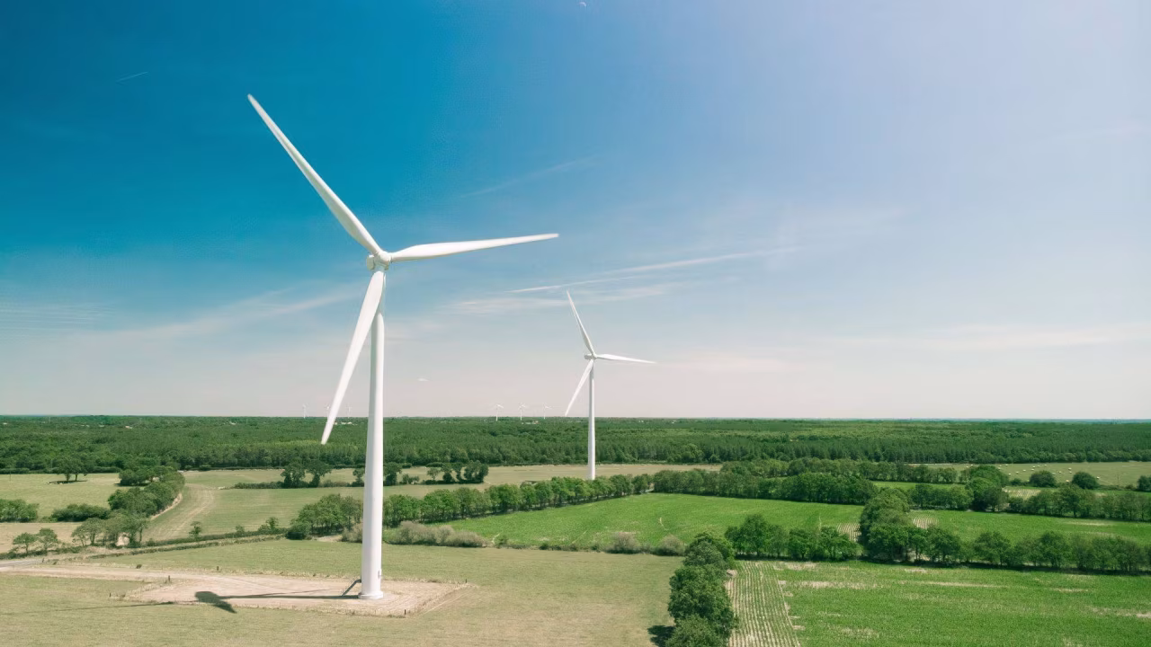 Landschap met heldere lucht en twee windturbines op groene weilanden illustreert duurzame windenergie en energietransitie in twente