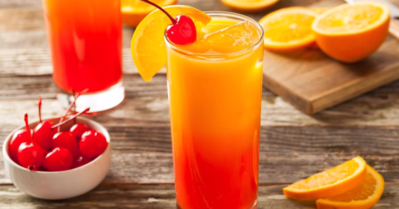 Close-up van een oranje-rode cocktail met sinaasappel en kers op een houten tafel, thema verfrissende tropische dranken, De sapsommelier en het gevecht tegen de bierkaai