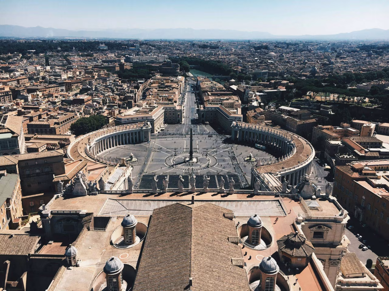 Luchtfoto van een historisch plein met hoge obelisk en kolonnade, overzicht over stad en rivier, nieuws april 2025
