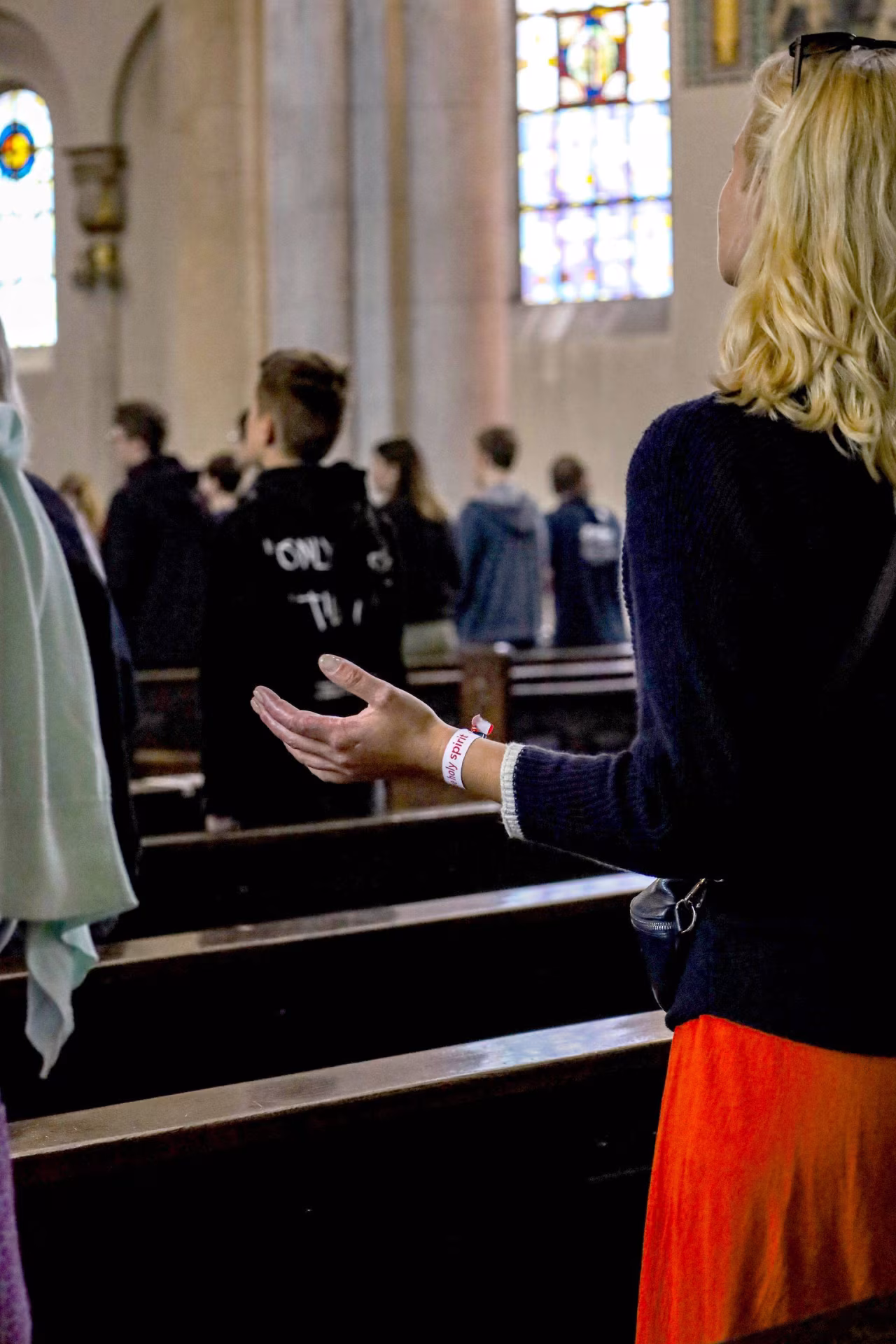 Kerkinterieur met figuur die hand uitstrekt in devotie tijdens spirituele bijeenkomst, thema verbinding in Twents mediaplatform