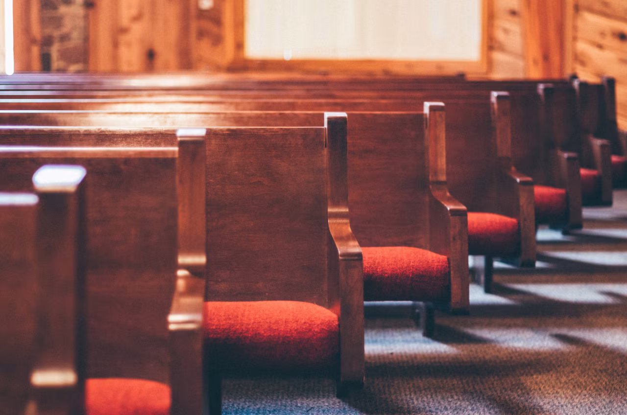 Rij houten kerkbanken met rode bekleding in serene kerkruimte met houten wanden en blauw tapijt nieuwsoverzicht 4-10 juli 2022