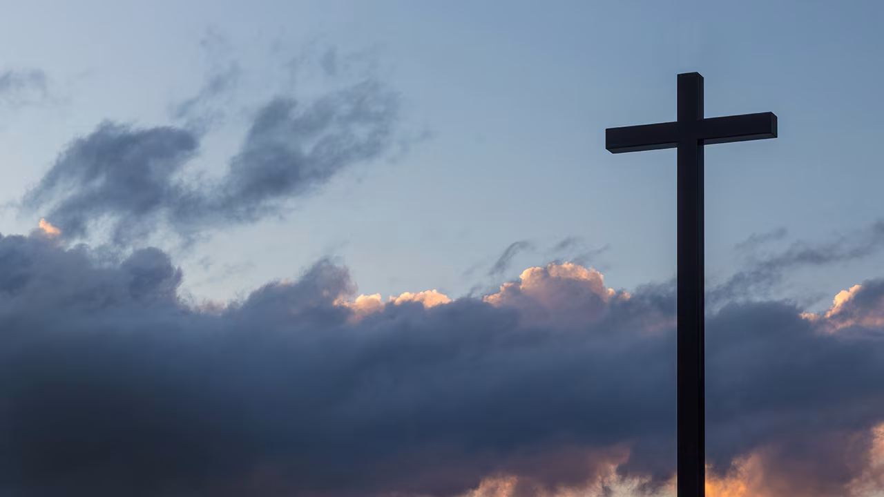 Silhouet van kruis tegen bewolkte lucht bij zonsondergang symbolisch voor conflict in twente patstelling