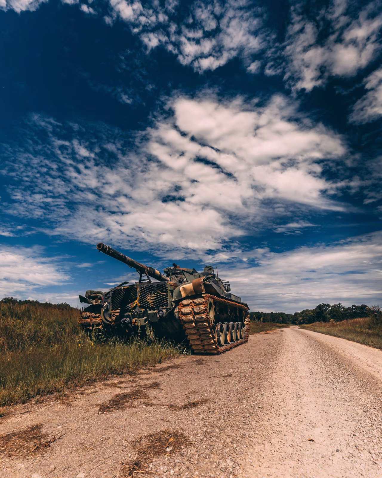 Zwaar gepantserde tank bij onverharde weg onder bewolkte blauwe hemel in afgelegen militair oefenterrein, thema De oorlog in Oekraïne