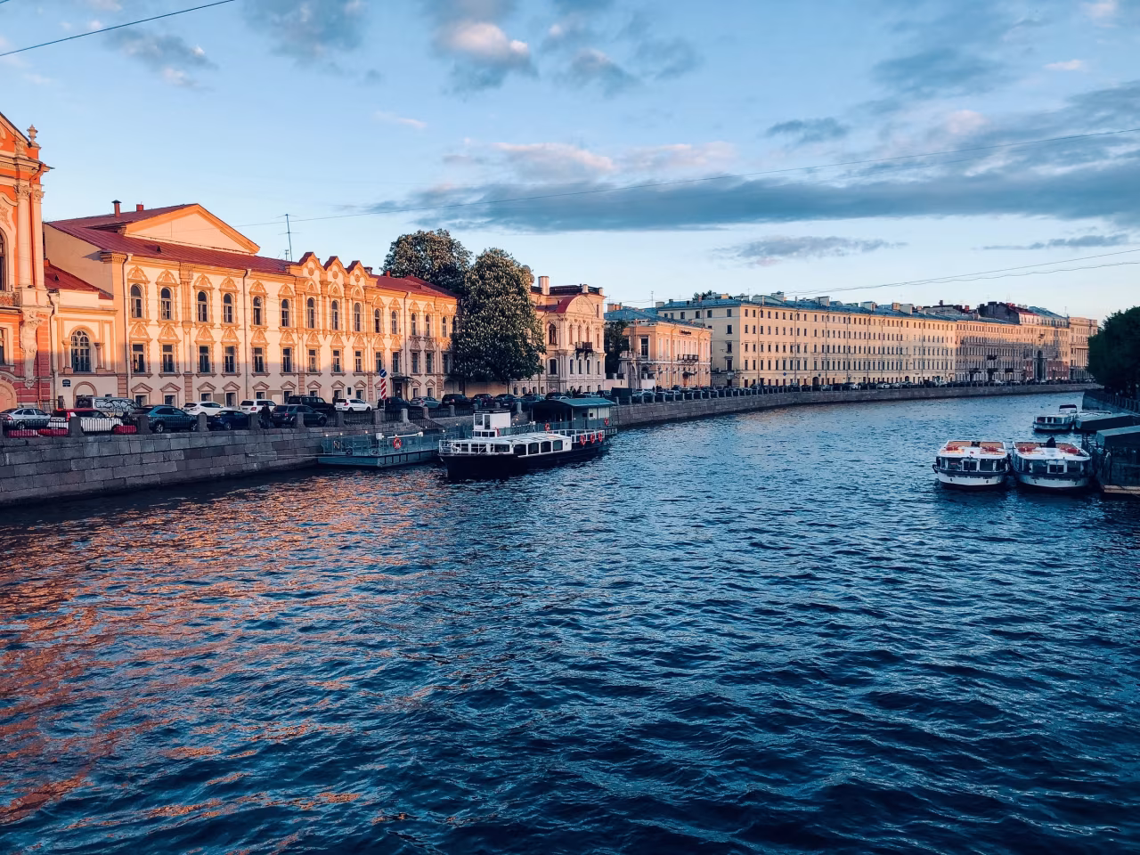 Sint-Petersburg rivierzicht met historische gebouwen langs de oever en aanlegsteigers, late namiddaglicht