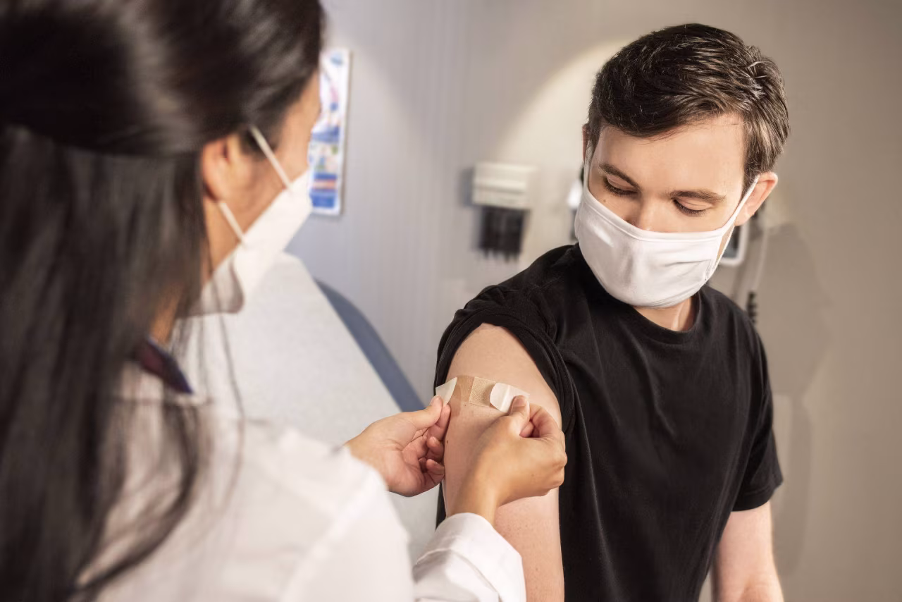 Vaccinatiearm wordt met pleister verzorgd in medische ruimte, passend bij nieuwsoverzicht juni-juli 2023 TKKR