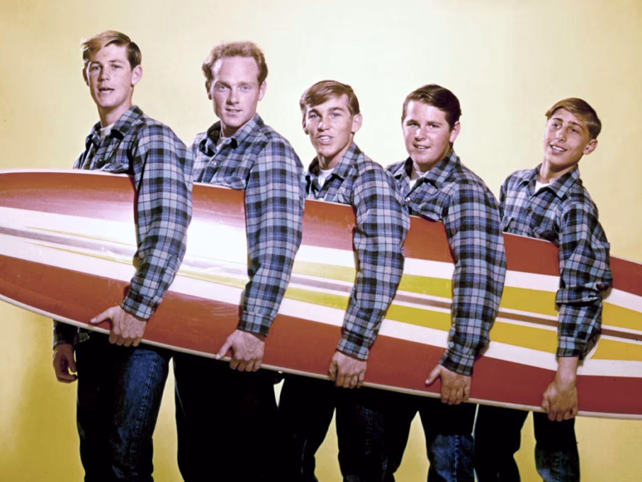 Nieuwsoverzicht 9-15 juni 2025: vijf mensen met surfplank met brede strepen wit geel oranje rood groepsportret studio