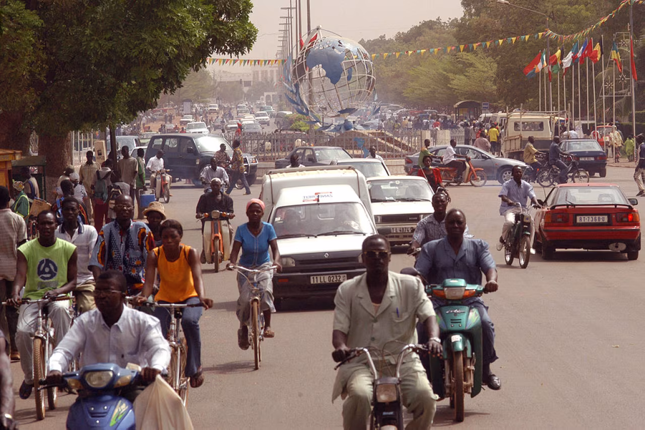 Drukke straat in ouagadougou met fietsen, scooters, auto's en metalen wereldbol kunstwerk - ouagadougou hertme en het afrika festival