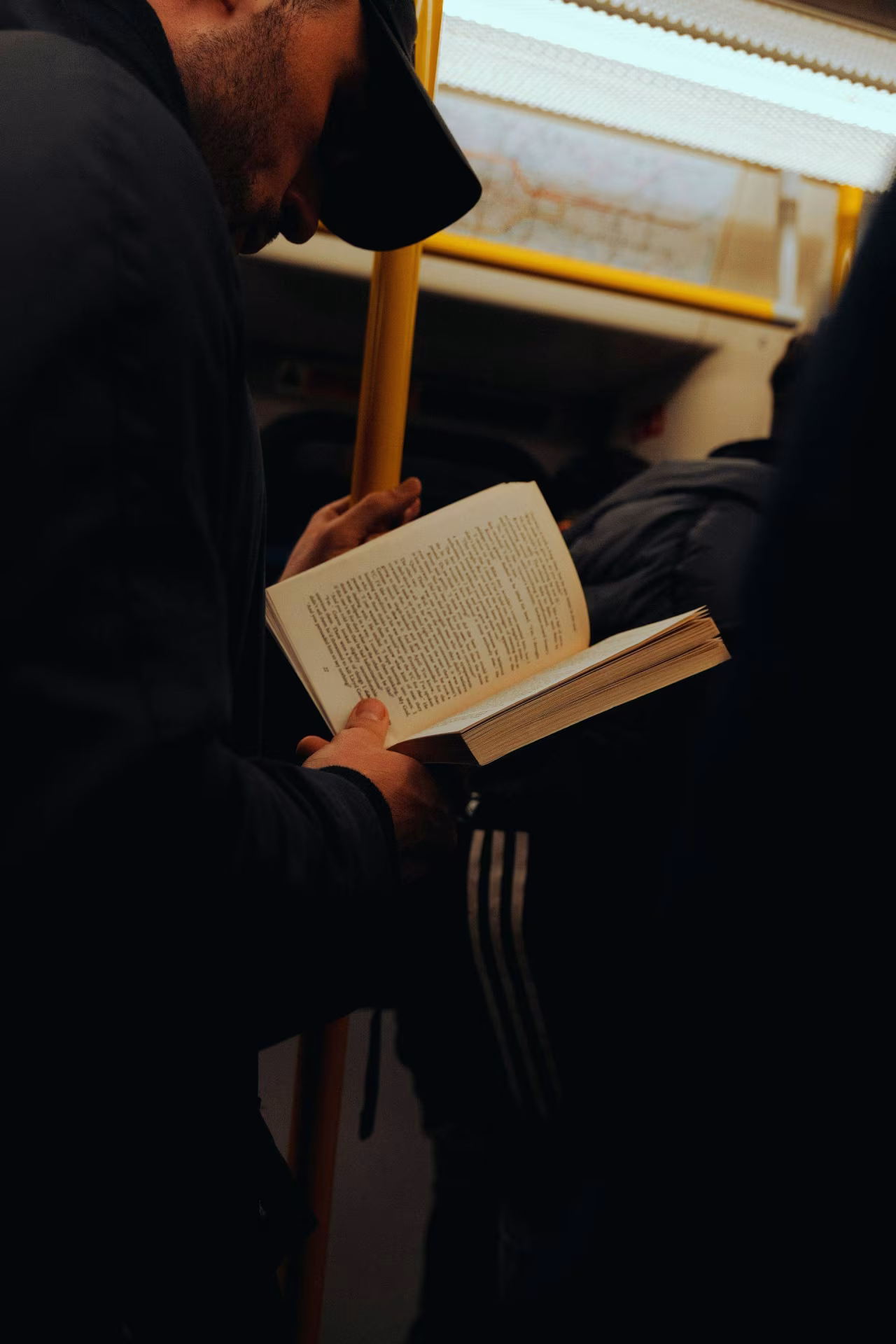 Boekenboek: afbeelding binnen openbaar vervoer van een reiziger die het boek 'Net niet verschenen boeken' leest, thema Twents mediaplatform over verleden heden toekomst