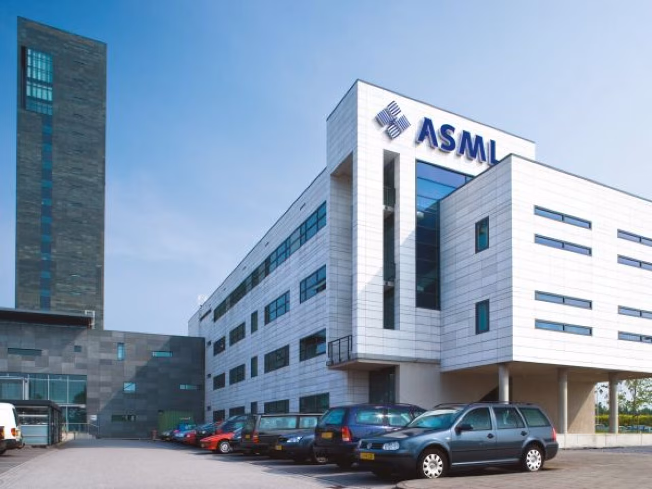 Modern kantoorgebouw asml met groot logo gevel en parkeergelegenheid bij zonnige blauwe hemel in nieuwsoverzicht tkkr