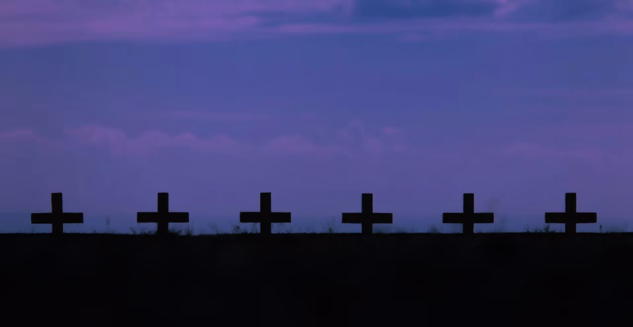 Zes zwarte kruisen op een rij tegen een paarse lucht, symboliseren herdenking in 'De oorlog in Oekraïne van ma 22 juli t/m zo 28 juli 2024'