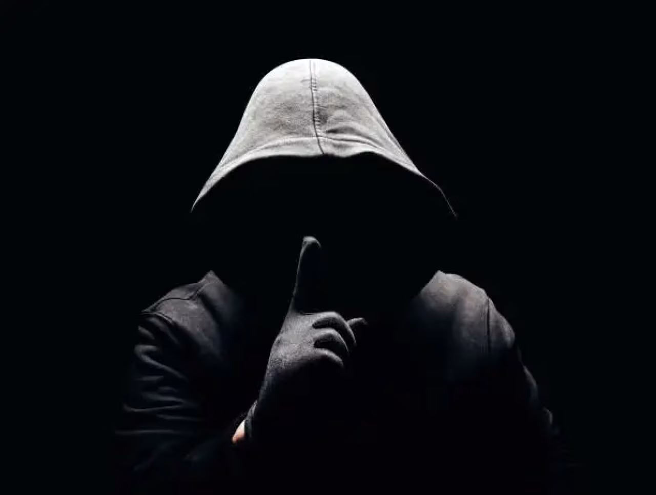 Donkere afbeelding met hoodie figuur die vinger op lippen houdt symboliseert stilte, geheimhouding, passend bij Voltrekking gedicht