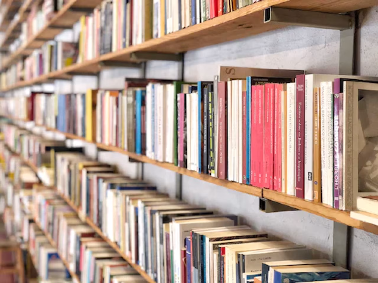 Boekenplanken met boeken in diverse kleuren en formaten in perspectief voor artikel gepruts in de marge op tkkrs mediaplatform over twente