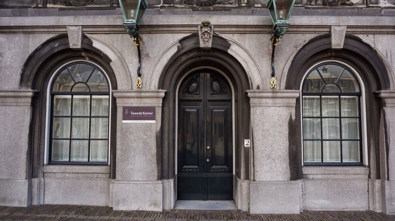 Vooraanzicht van het stenen gebouw met drie bogen, centrale dubbele deur en bord met tekst 'Tweede Kamer' volgens nieuwsoverzicht juli 2022