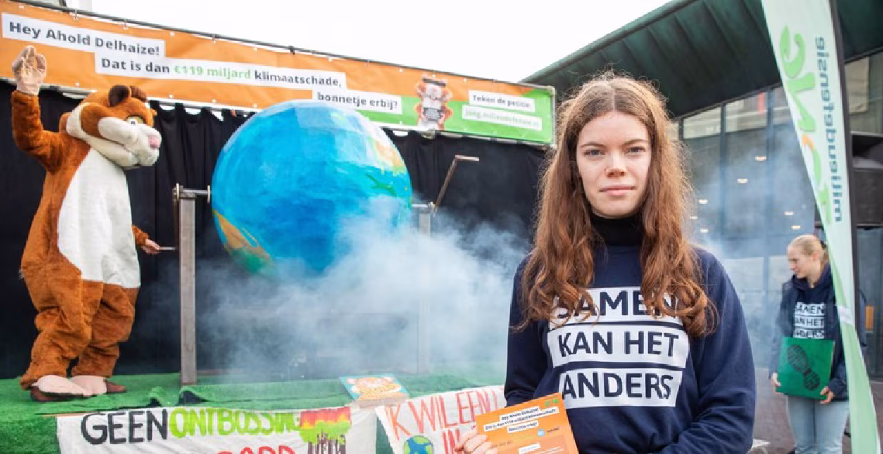 Beeld van klimaatevenement met grote aarde bol, rook, en tekst 'SAMEN KAN HET ANDERS' als oproep tot samenwerking