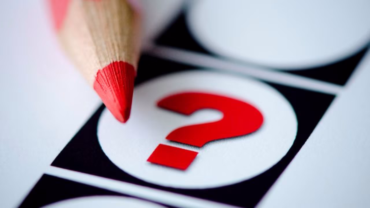 Rood potlood gericht op rood vraagteken binnen witte cirkel op zwarte achtergrond, symbool voor onbepaalde keuze in nieuwsoverzicht