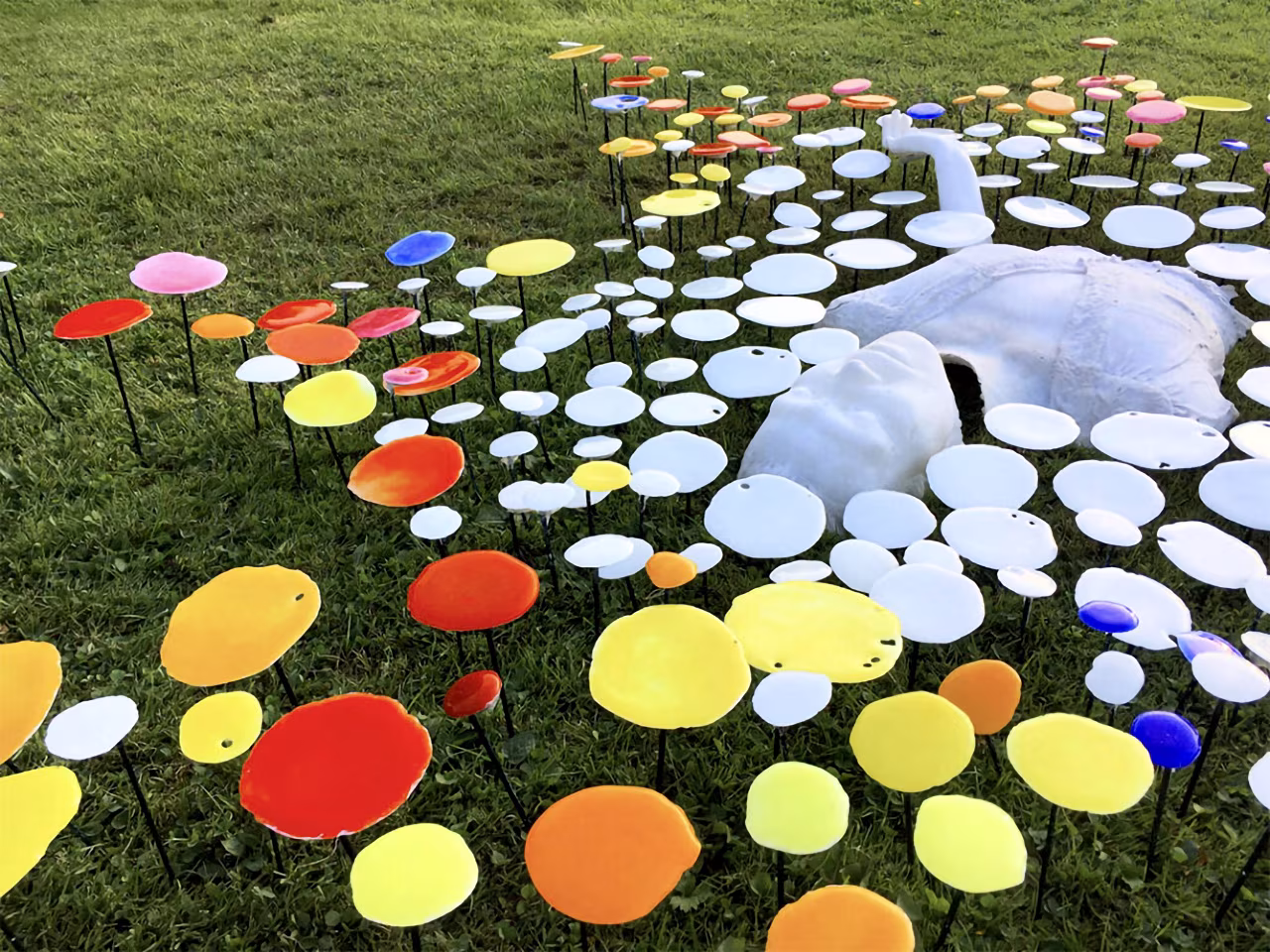 Glasrijk Tubbergen 25 jaar glaskunst met kleurrijke cirkels en witte abstracte vorm in grasveld, kunstwerk Colour of life