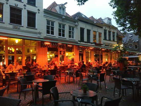 Gezellig stadsterras bij avond met historische panden en warme verlichting, sfeer voor Terrasschaamte en de kronkels van ons brein