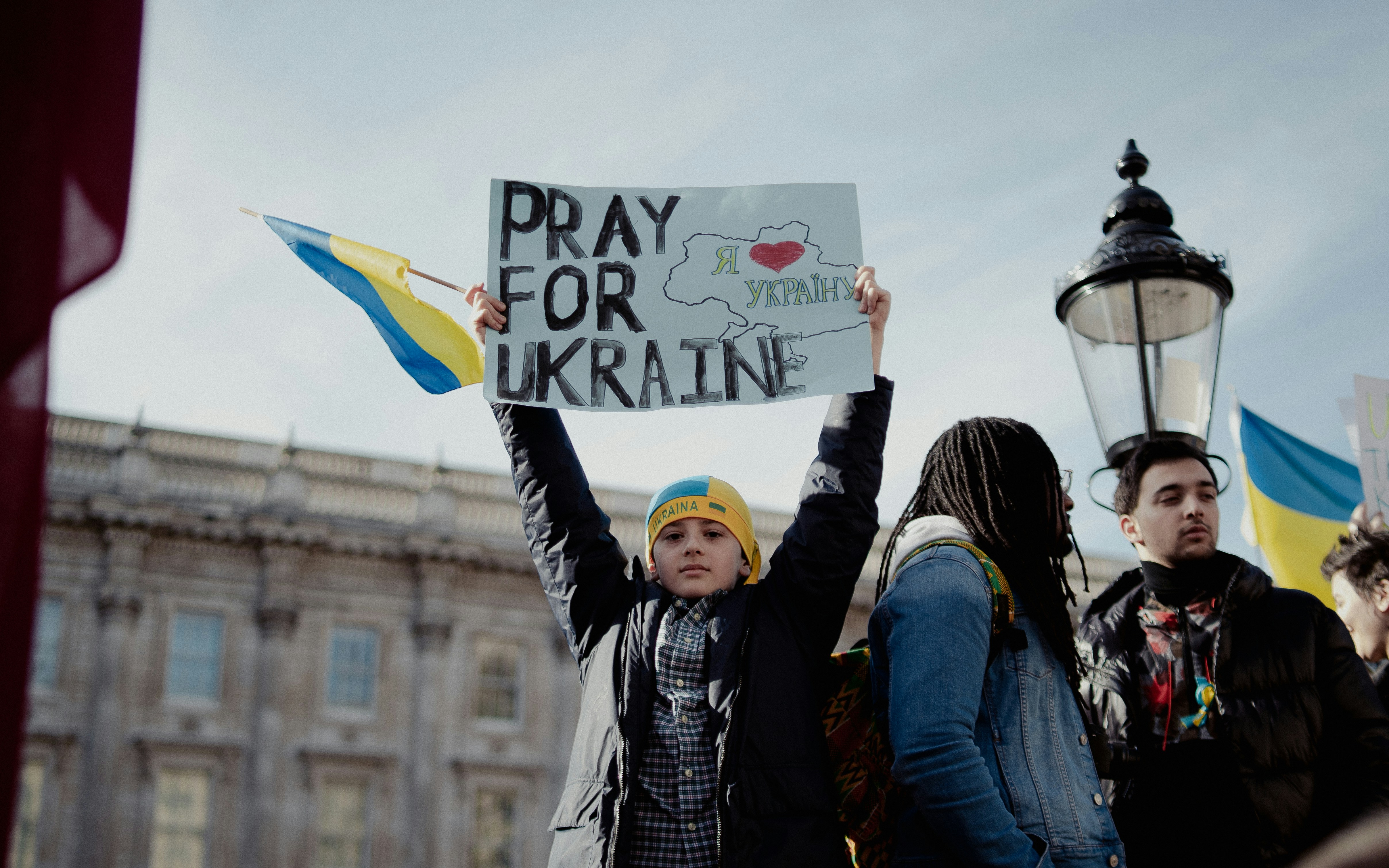Demonstratie met bord waarop staat Pray for Ukraine en Oekraïense vlag kleuren, steun bij De oorlog in Oekraïne juni 2024