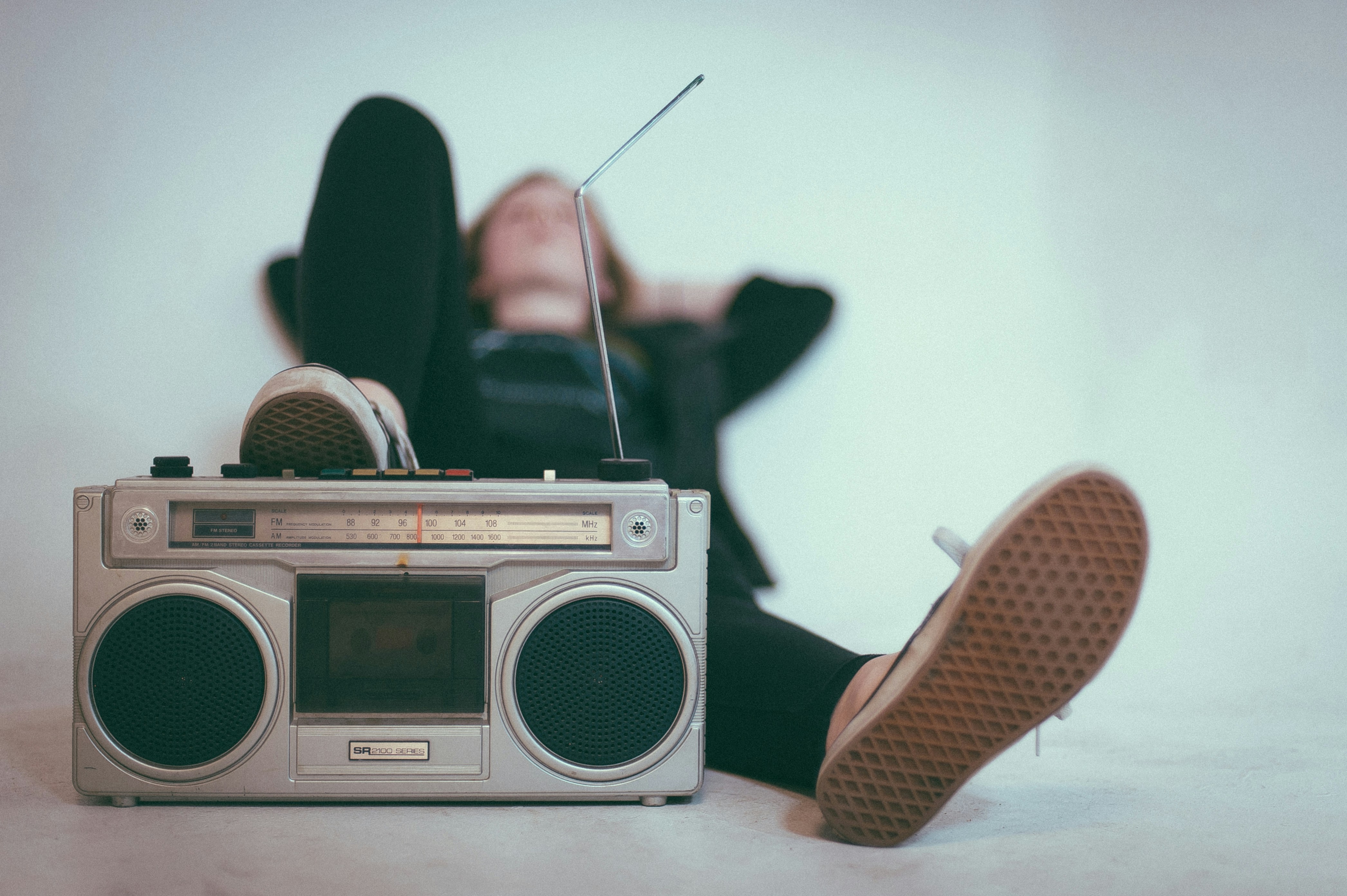Radio-cassette speler met antenne en grote speakers op de voorgrond, persoon ligt ontspannen op de achtergrond, nieuwsoverzicht van 24 t/m 30 juni 2024 over Brexit, Dagestan aanslagen, Mekka bedevaart, inkomens, natuurbranden, Krim conflict, huurwetten, EU topbanen, Kenia protesten, toeslagenschandaal, radio populariteit, overheid rechtszaken, EK voetbal, Oranje optimisme, Filippijnen China conflict